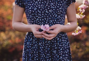 woman clasping flower in front of stomach