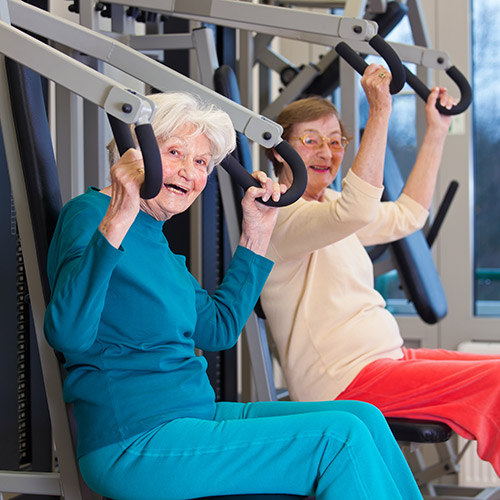 Two older ladies lifting weights at the gym